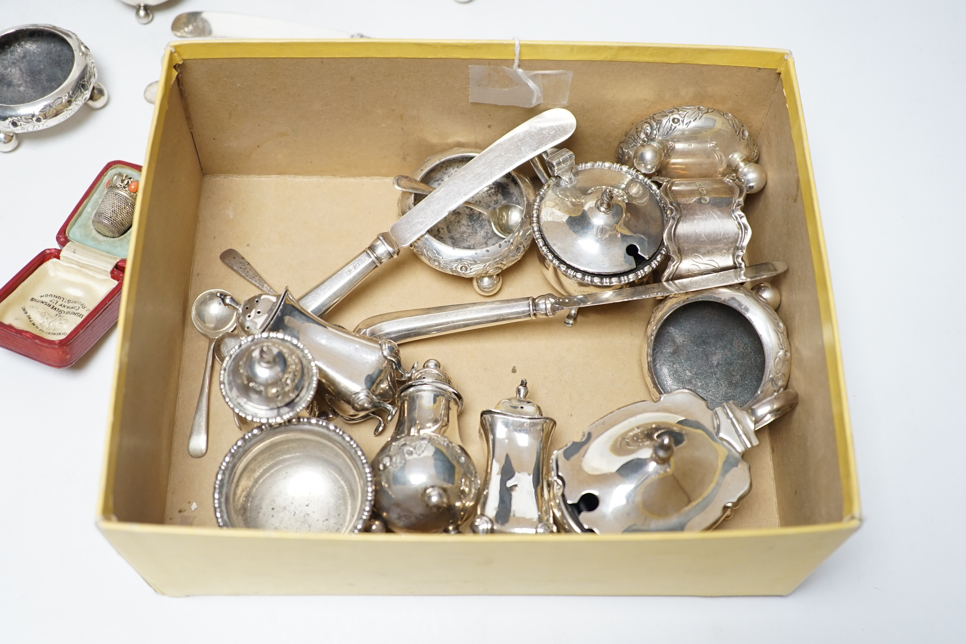 Twelve assorted silver condiments, including a set of four Edwardian bun salts, William Hutton & Sons, London, 1903, a set of six silver handled tea knives, a small silver trophy cup, silver napkin ring, cased silver thi